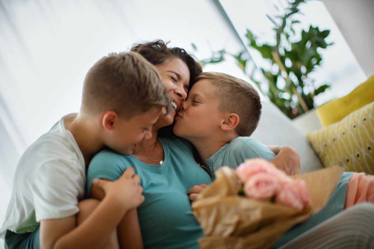 Due fratellini riempiono di coccole e baci la mamma