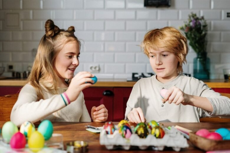 Bambini seduti in cucina stanno colorando le uova