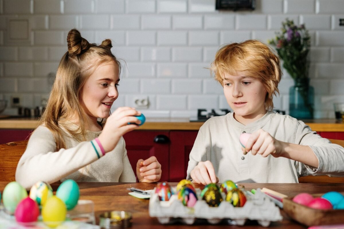Bambini seduti in cucina stanno colorando le uova