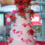 Torta con base rosa e petali rosa acceso e rossi