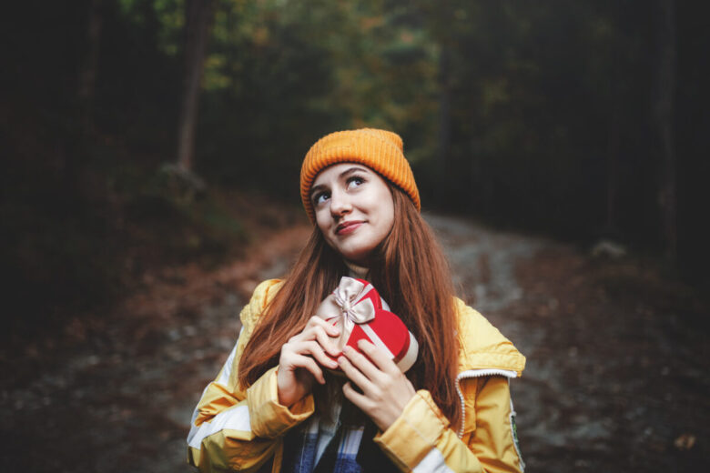 Ragazza in primo piano che stringe un pacco regalo a forma di cuore