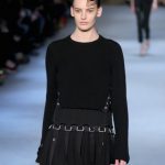 Diesel Black Gold gonna con dettagli metallici e cinghie indossata con un maglione nero collo alto