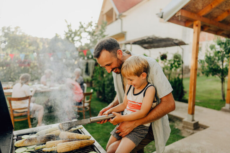 Padre e figlio stanno facendo un barbecue in giardino