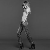 Look casual composto da maglia a righe bianche e grigie, jeans regular leggermente larghi alla caviglia, stivaletti neri alla caviglia con tacco