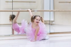 Little ballerina girl in a pink tutu. Adorable child dancing classical ballet in a white studio.