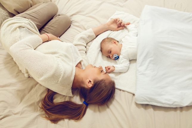 Mamma che guarda il suo bambino dormire