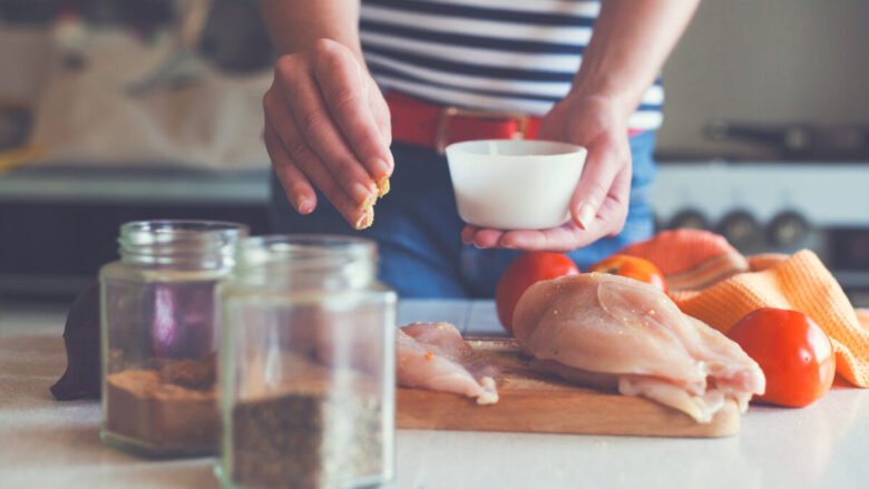 Ragazza sta marinando il pollo prima di cucinarlo