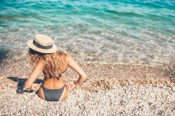 ragazza bionda in riva al mare di spalle