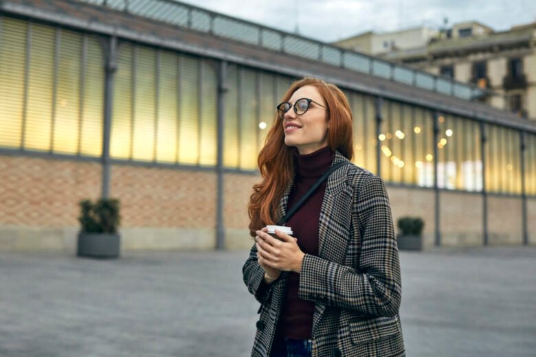 Una ragazza passeggia in città con in mano un caffè da asporto