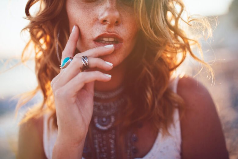 Close up di una ragazza in spiaggia che indossa molti gioielli, sia anelli che collane