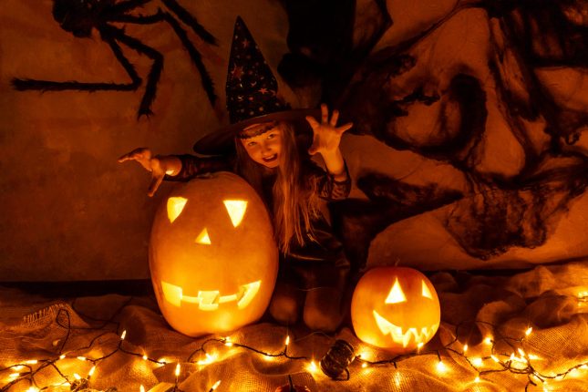 Una bambina travestita per halloween gioca con delle zucche