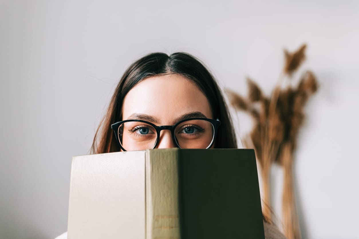 donna sorridente che si nasconde dietro ad un libro