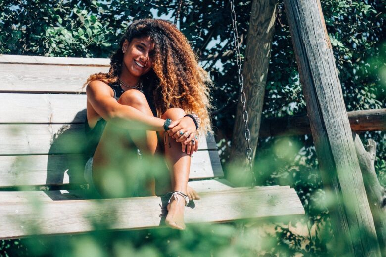 ragazza con capelli ricci sorride sul dondolo