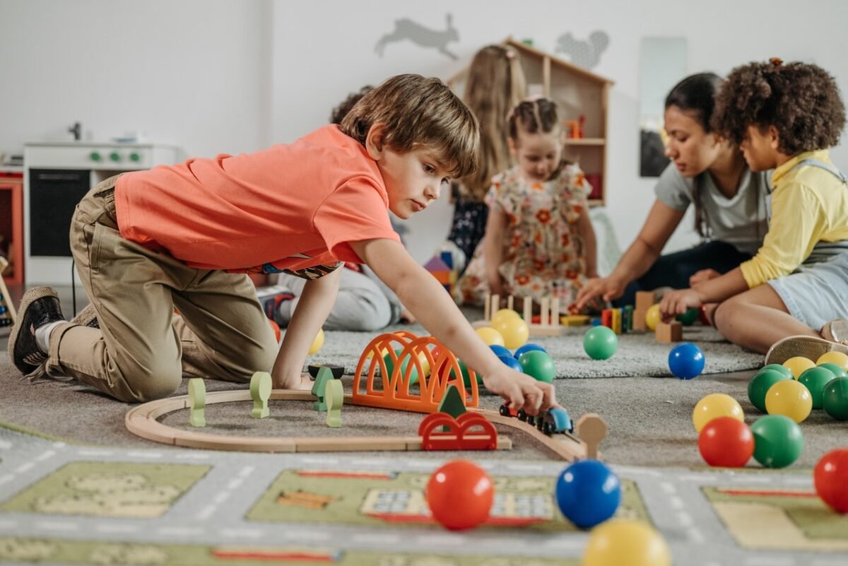Bambini che giocano con un trenino dentro un asilo
