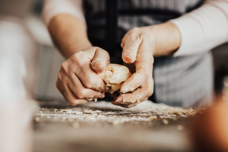 Mani che impastano in cucina
