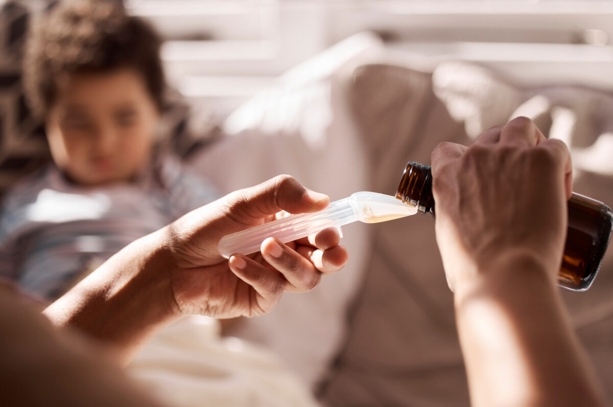 Una mamma prepara un cucchiaino di sciroppo per il bambino