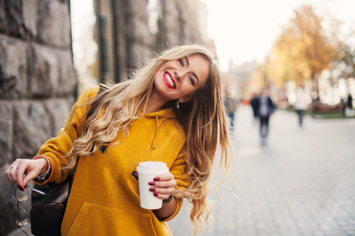 Una ragazza bionda con un vestito giallo sorride