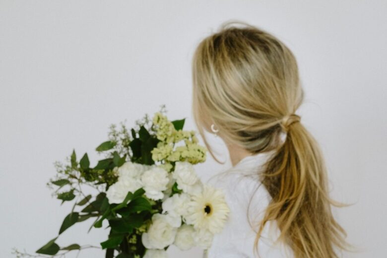 ragazza di spalle con capelli legati e mazzo di fiori
