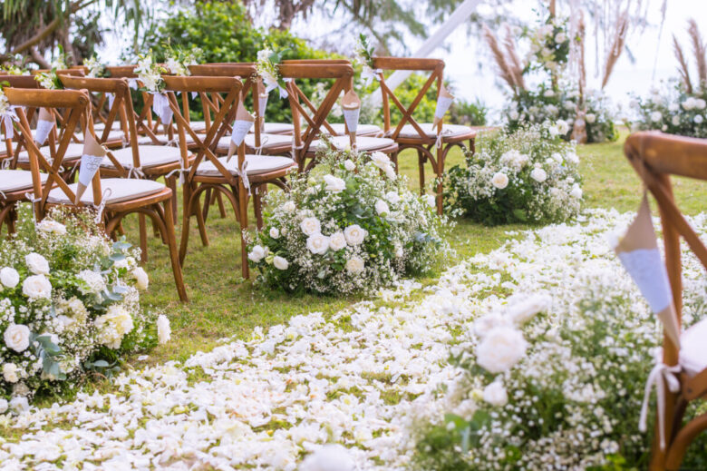 Matrimonio all'aperto, sedie addobbate e fiori che accompagnano l'ingresso degli sposi