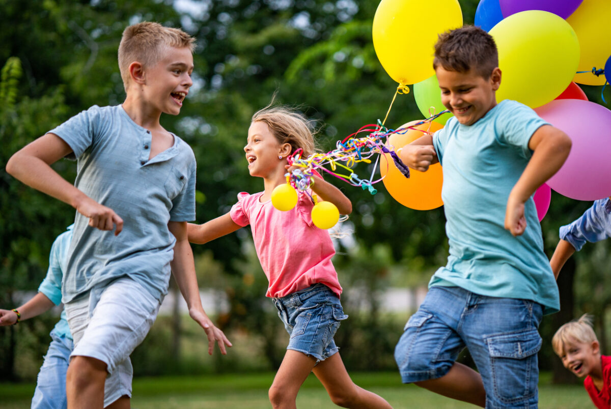 Bambini che festeggiano il compleanno al parco con palloncini