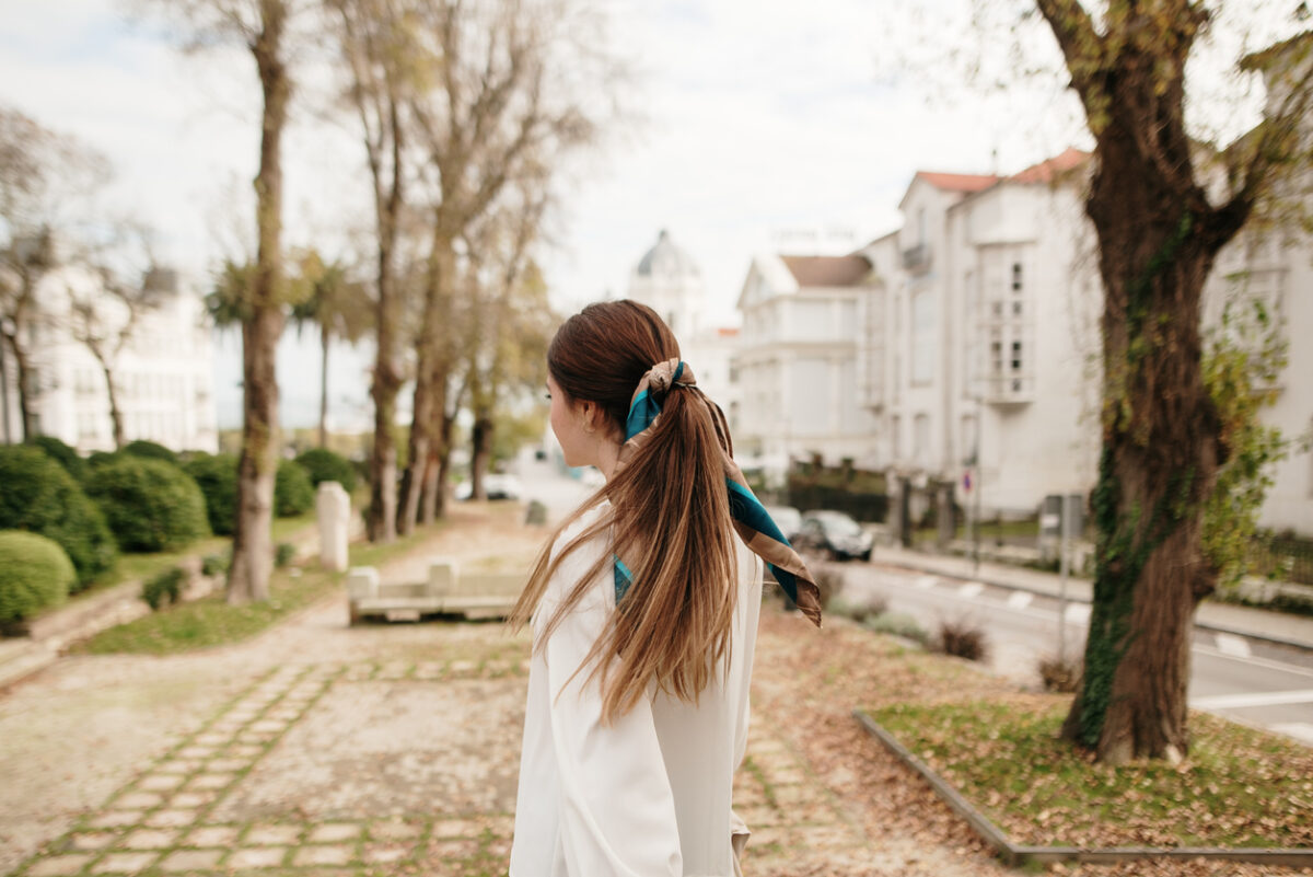 Ragazza con coda di cavallo allacciata con un foulard mentre passeggia