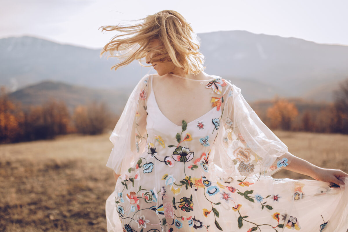 Donna con abito floreale fotografata in un campo
