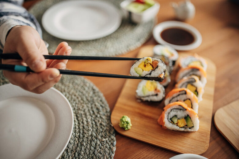 Ragazza che mangia sushi con le bacchette
