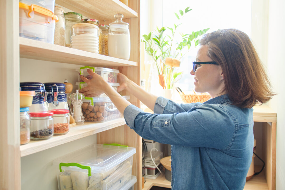 donna sta sistemando le conserve e il cibo in dispensa