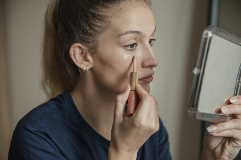 ragazza che si mette il correttore davanti allo specchio