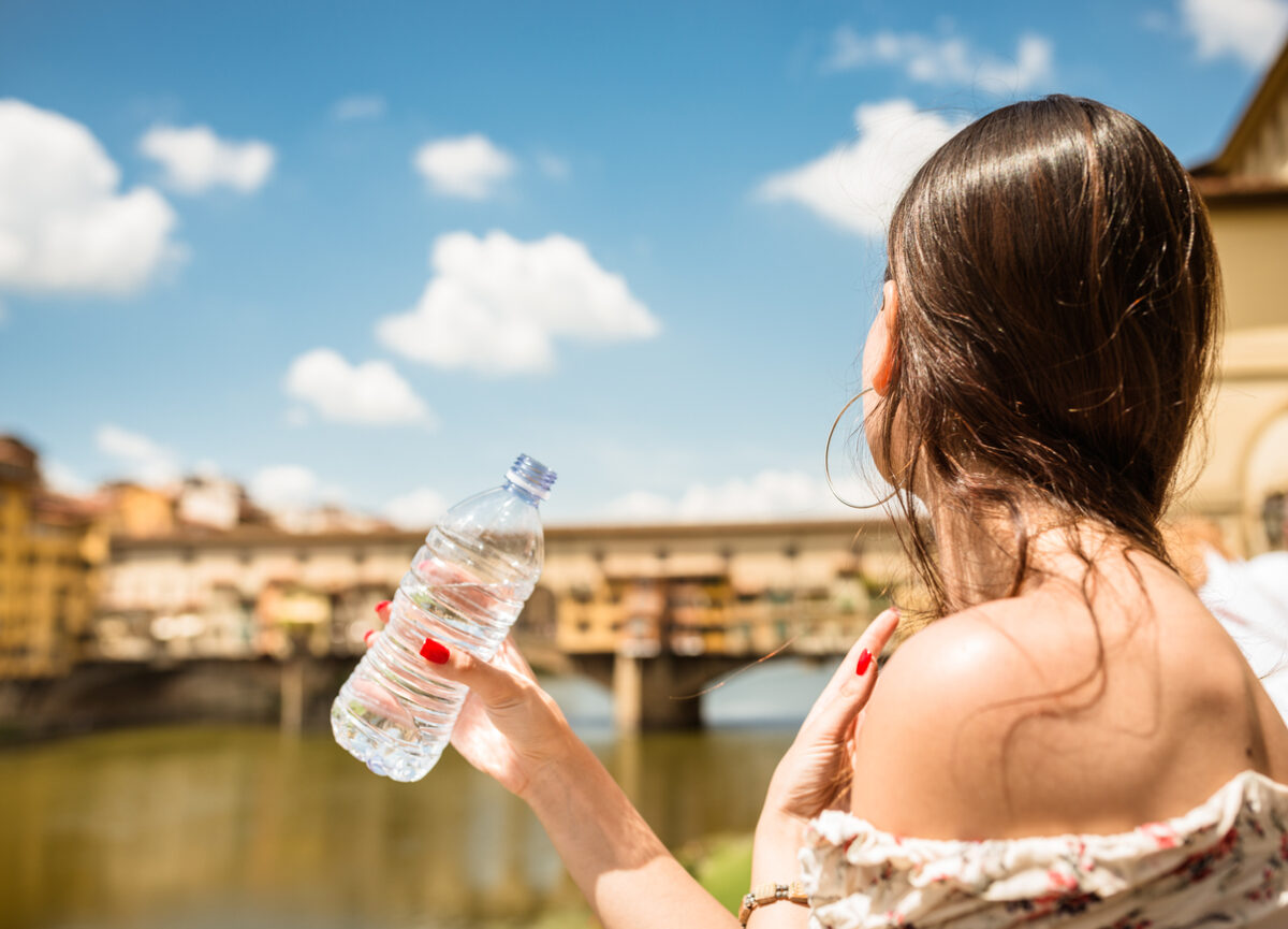 Una ragazza sta bevendo acqua in città durante una giornata particolarmente assolata