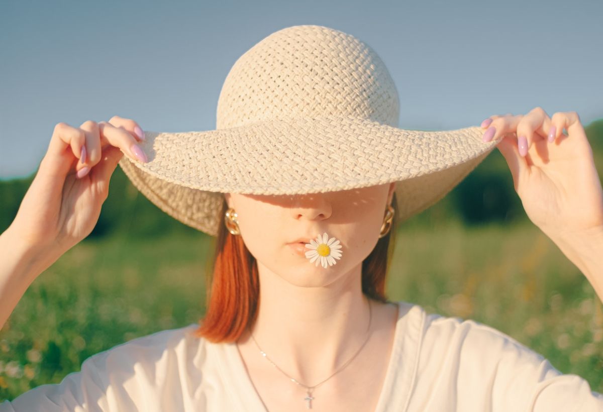 ragazza con cappello di paglia in un campo di fiori