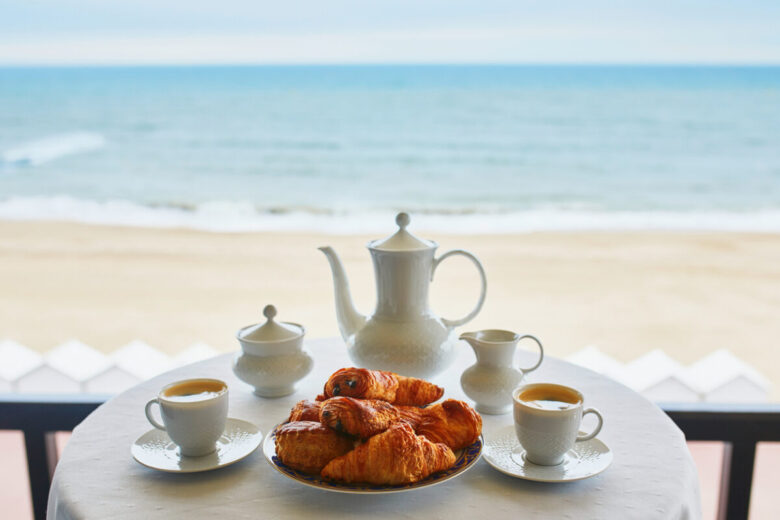 Tavola apparecchiata vista mare con croissant e the