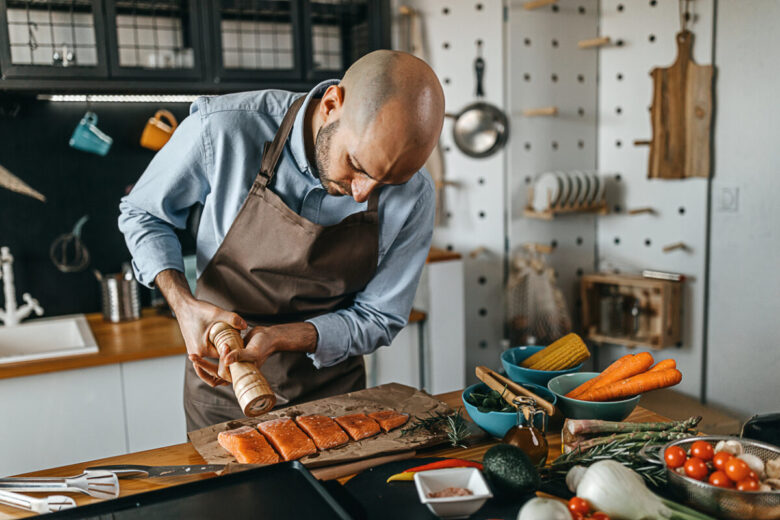 un ragazzo sta cucinando il salmone in cucina
