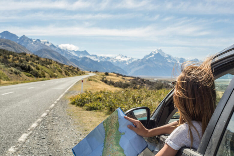Ragazza che si sporge dal finestrino dell'auto con una mappa