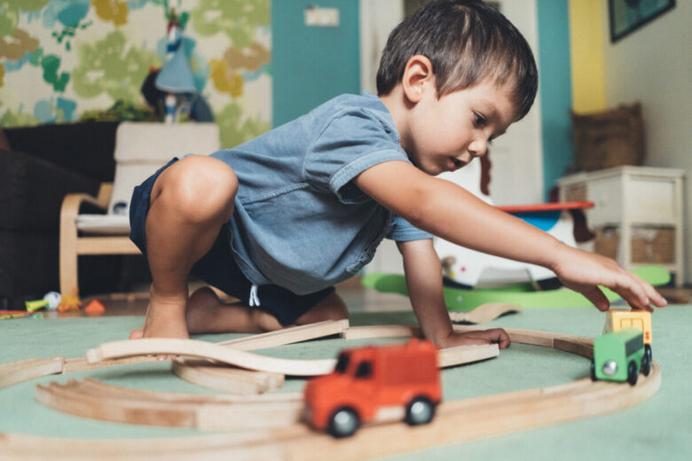 Bambino gioca in camera con il suo trenino di legno