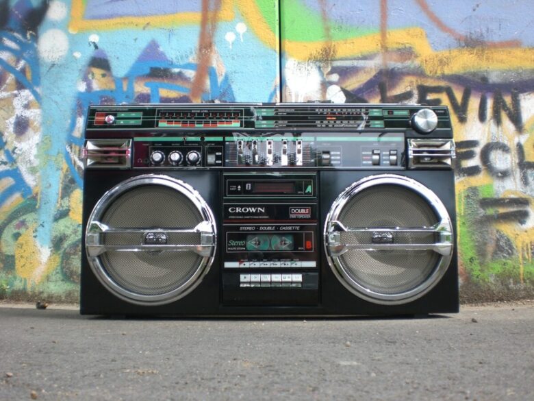 Una radio stereo poggiata per terra con muro in graffiti dietro