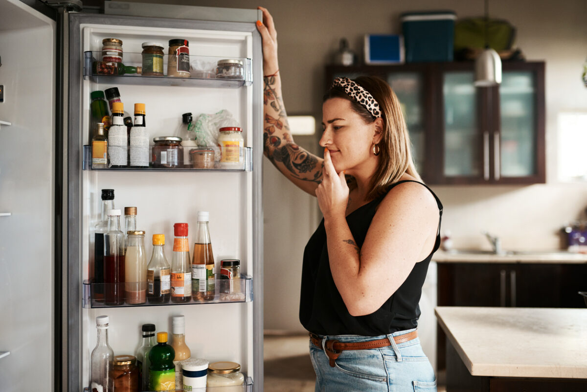 Una ragazza ha aperto il frigo e sta guardando cosa cucinare