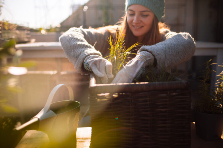 Una ragazza sta piantando piante e fiori in balcone in inverno