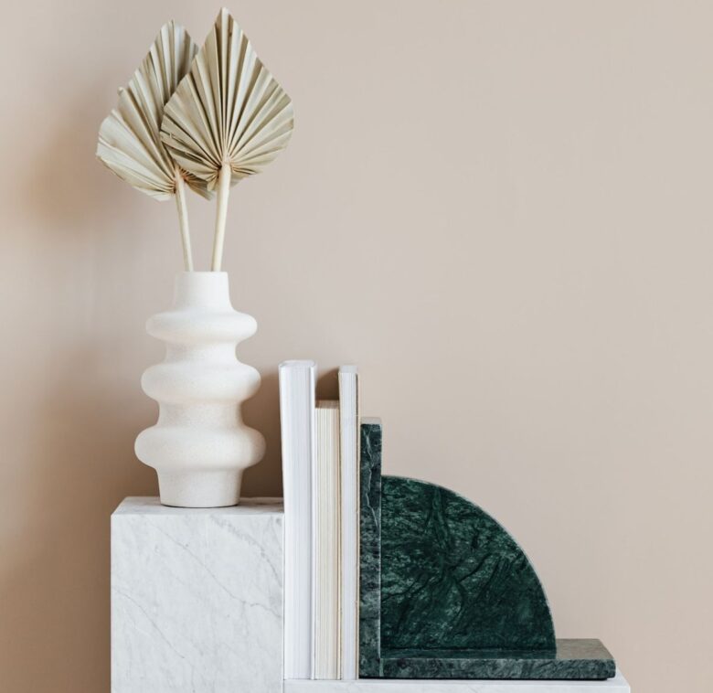Vaso in ceramica appoggiato al muro con altri elementi di arredo in marmo.