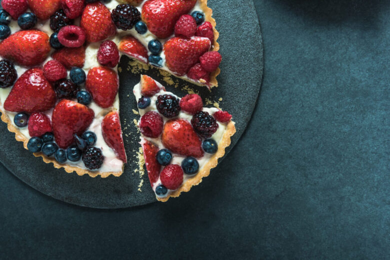 Crostata fredda allo yogurt e frutti di bosco con una fetta tagliata