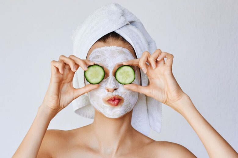 Donna con una maschera sul viso che tiene due cetrioli sugli occhi