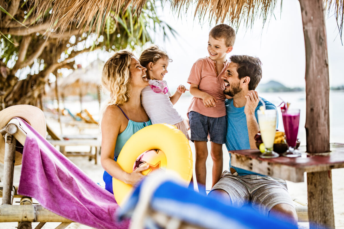 Young happy family talking while spending a summer day on a deck chair at the beach.