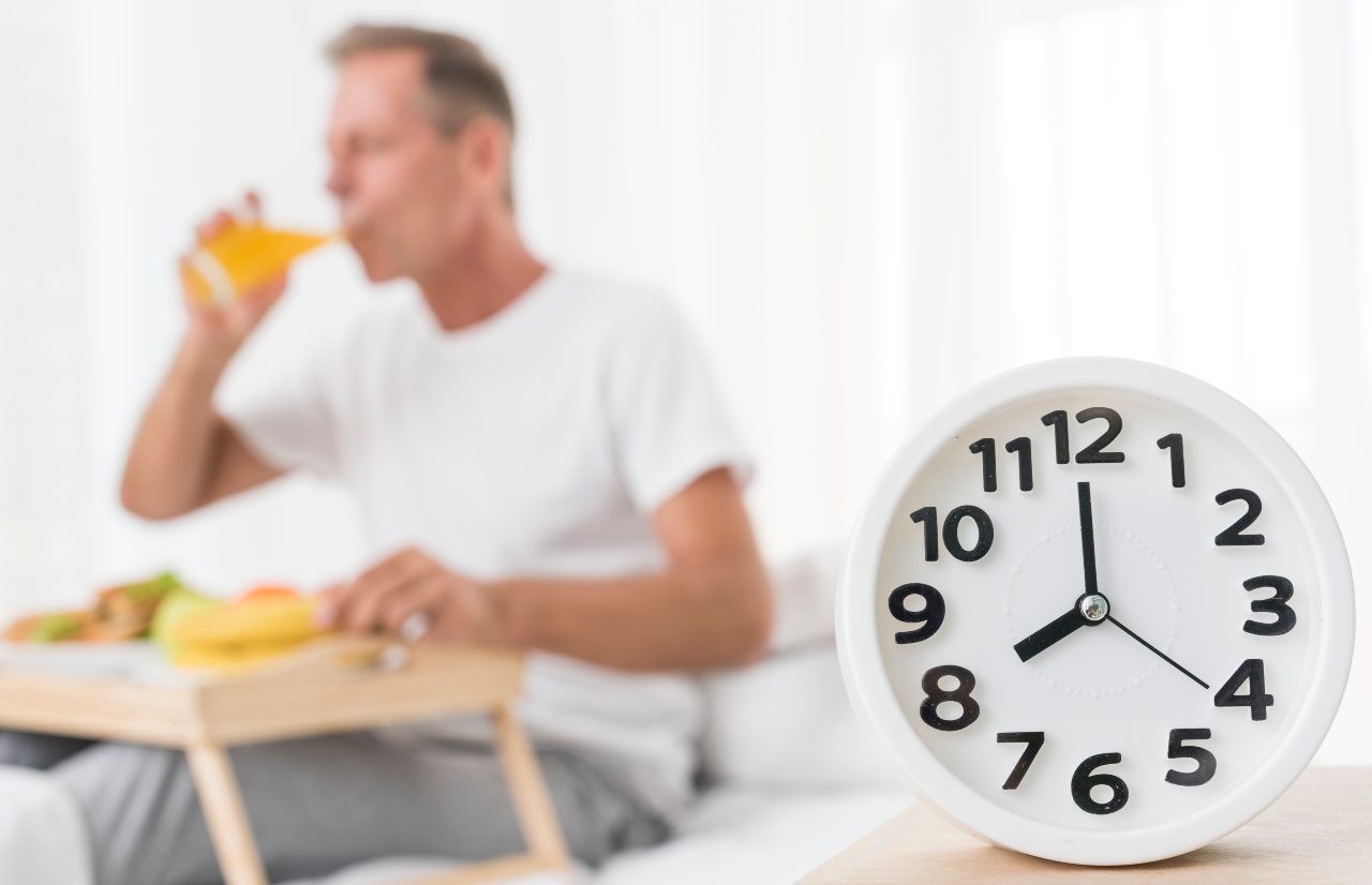 orologio e uomo che fa colazione a letto